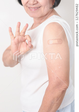 Elderly Woman with bandage after received vaccine. Vaccination and Immunization for Influenza, Herpes Zoster, Tetanus, Covid 19 booster, Dengue, Encephalitis, Rabies, Pneumococcal, IPD, RSV Vaccines 127629482