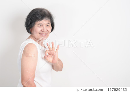 Elderly Woman with bandage after received vaccine. Vaccination and Immunization for Influenza, Herpes Zoster, Tetanus, Covid 19 booster, Dengue, Encephalitis, Rabies, Pneumococcal, IPD, RSV Vaccines 127629483