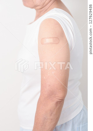 Elderly Woman with bandage after received vaccine. Vaccination and Immunization for Influenza, Herpes Zoster, Tetanus, Covid 19 booster, Dengue, Encephalitis, Rabies, Pneumococcal, IPD, RSV Vaccines 127629486