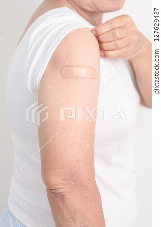 Elderly Woman with bandage after received vaccine. Vaccination and Immunization for Influenza, Herpes Zoster, Tetanus, Covid 19 booster, Dengue, Encephalitis, Rabies, Pneumococcal, IPD, RSV Vaccines 127629487