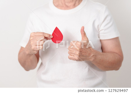 Elderly woman with red Blood drop paper for concept of June World Blood Donor day, Donation, April Hemophilia awareness day, May Thalassemia Day, Anemia awareness, June Sickle Cell and Blood Disorders Elderly woman with red Blood drop paper for concept of June World Blood Donor day, Donation, April Hemophilia awareness day, May Thalassemia Day, Anemia awareness, June Sickle Cell and Blood Disorders 127629497