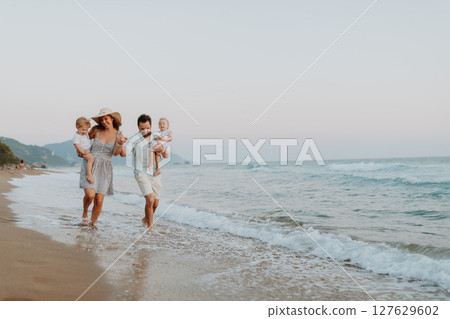 A family with two toddler children walking on beach on summer holiday at sunset. A family with two toddler children walking on beach on summer holiday at sunset. 127629602