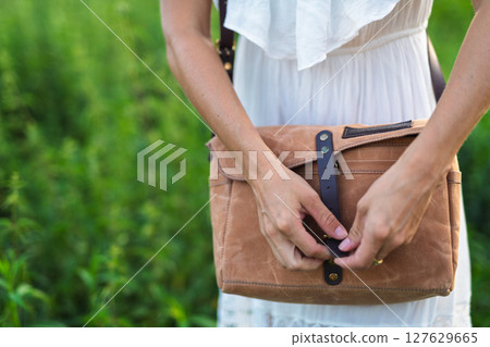 Woman fastening leather strap on stylish brown shoulder bag Woman fastening leather strap on stylish brown shoulder bag 127629665