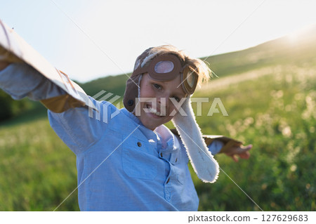 A small boy playing on a meadow in nature, with goggles and wings as if flying. A small boy playing on a meadow in nature, with goggles and wings as if flying. 127629683