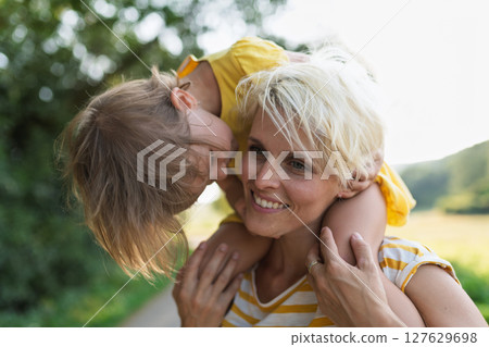 A portrait of mother carrying little girl on shoulders. 127629698