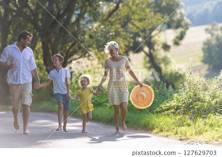 A family with small children running barefoot on a road in summer. 127629703