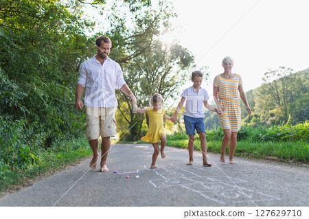 A family with small children running barefoot on a road in summer. 127629710