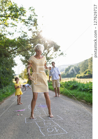 Family having fun, playing hopscotch during warm summer day. 127629717