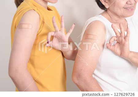 Adult and Elderly Woman with bandage after received vaccine. Vaccination and Immunization for Influenza, HPV, Zoster, IPD, DTP, Dengue, Encephalitis, Rabies, Pneumococcal Hepatitis B and Covid vaccine 127629726
