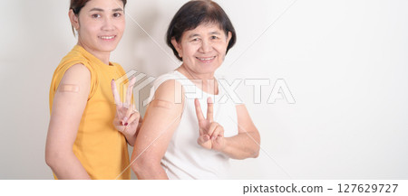 Adult and Elderly Woman with bandage after received vaccine. Vaccination and Immunization for Influenza, HPV, Zoster, IPD, DTP, Dengue, Encephalitis, Rabies, Pneumococcal Hepatitis B and Covid vaccine 127629727
