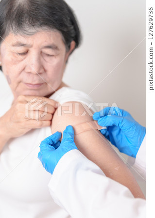 Elderly Woman with bandage after received vaccine. Vaccination and Immunization for Influenza, Herpes Zoster, Tetanus, Covid 19 booster, Dengue, Encephalitis, Rabies, Pneumococcal, IPD, RSV Vaccines 127629736