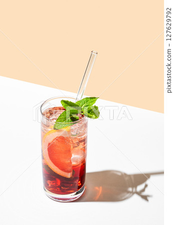 Refreshing cocktail with grapefruit, mint and ice in a glass on a white yellow background Refreshing cocktail with grapefruit, mint and ice in a glass on a white yellow background 127629792