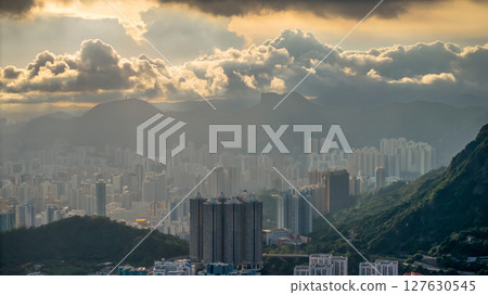 June 8 2025 Urban Skyscrapers and Lush Hills Under Sunset Illuminated Clouds 127630545