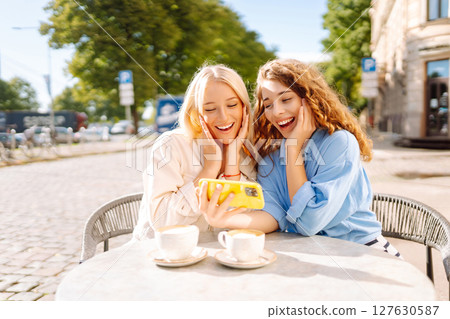 Young women enjoying in coffee and having fun with smartphone. Coffee break after shopping. 127630587