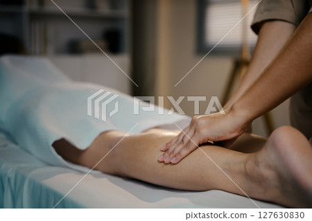 Therapist gently massaging client leg to promote circulation and relaxation 127630830
