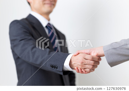 A businessman and a businesswoman in suits shaking hands A businessman and a businesswoman in suits shaking hands 127630976
