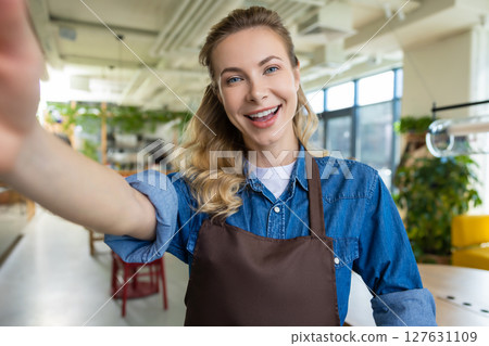 Cute blonde woman in apron making selfie and smiling Cute blonde woman in apron making selfie and smiling 127631109