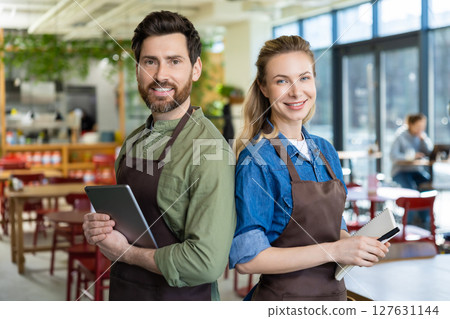 Two waiters in pizzeria looking happy and confident wile waiting for the clients Two waiters in pizzeria looking happy and confident wile waiting for the clients 127631144