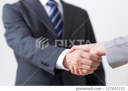 A businessman and a businesswoman in suits shaking hands A businessman and a businesswoman in suits shaking hands 127631151