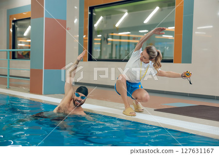Young man having a workout with a female coach in the pool Young man having a workout with a female coach in the pool 127631167