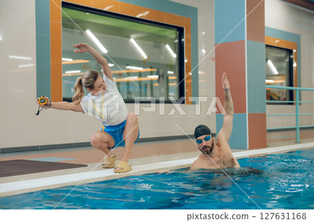 Young man having a workout with a female coach in the pool Young man having a workout with a female coach in the pool 127631168