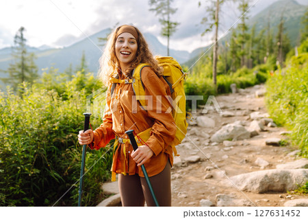 Young woman traveler hiking poles on trail among the mountains. Hiking. Active lifestyle. Young woman traveler hiking poles on trail among the mountains. Hiking. Active lifestyle. 127631452