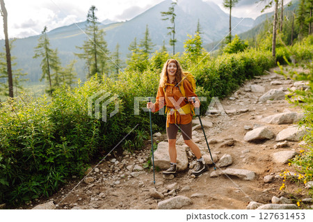Young woman traveler hiking poles on trail among the mountains. Hiking. Active lifestyle. Young woman traveler hiking poles on trail among the mountains. Hiking. Active lifestyle. 127631453