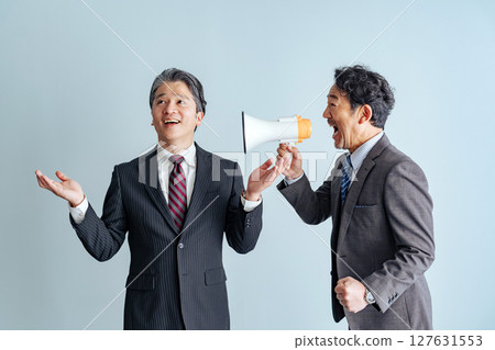 一位中年男性商務人士透過擴音器向中老年男性發出呼叫 一位中年男性商務人士透過擴音器向中老年男性發出呼叫 127631553