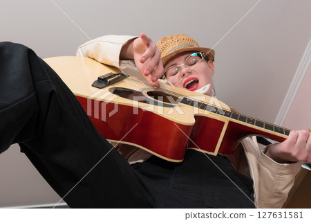 Expressive female guitarist and singer songwriter playing acoustic guitar and sings song with eyes closed. Low angle view of woman guitarist, selective focus on musician's hand while playing guitar 127631581