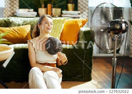 Joyful Woman Relaxes with Fan in Summer Heat 127632022