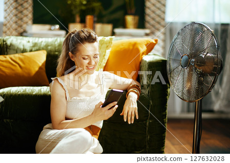 Woman Relaxing with Smartphone and Cooling Fan 127632028