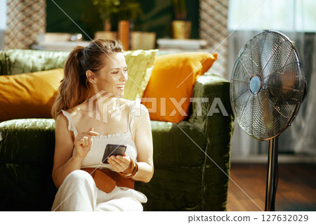 Woman Communicating on Phone by Cooling Fan Woman Communicating on Phone by Cooling Fan 127632029