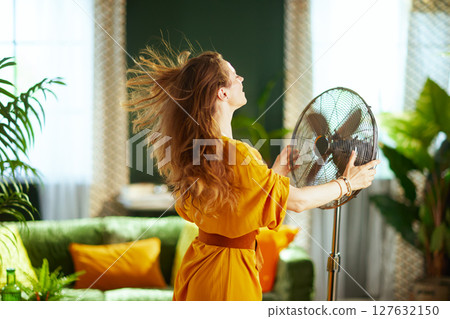 Woman Enjoying Fan Breeze on a Hot Summer Day 127632150
