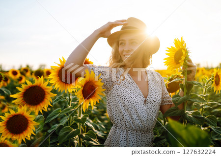 Happy young woman surrounded by yellow sunflowers in full bloom, traveling on holiday. 127632224