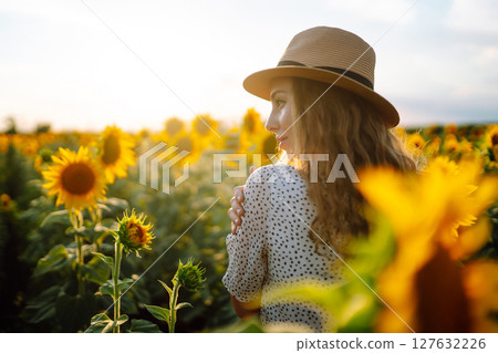 Happy young woman surrounded by yellow sunflowers in full bloom, traveling on holiday. 127632226