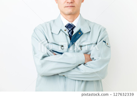 A middle-aged male businessman wearing green work clothes and folding his arms 127632339