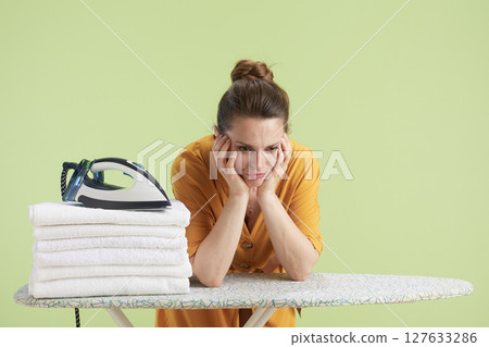 Tired woman leaning on hands beside laundry 127633286