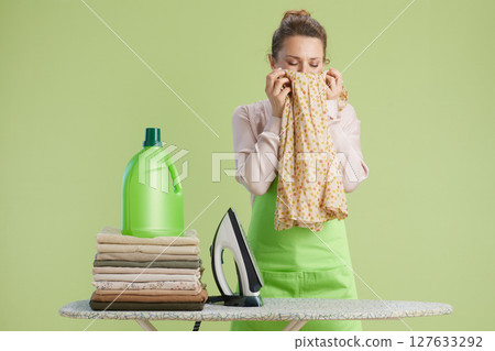 Woman enjoying fresh laundry scent at ironing board Woman enjoying fresh laundry scent at ironing board 127633292