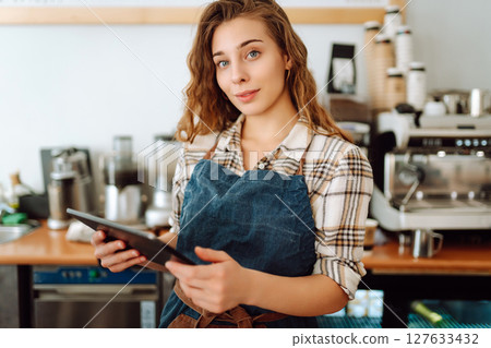 Successful small business owner stands behind counter of coffee shop with digital tablet takes order 127633432