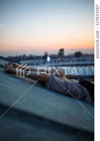 Beautiful woman on rooftop posing at sunset. Woman enjoys atmosphere of city of freedom. Relaxation. 127633567