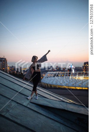 Beautiful woman on rooftop posing at sunset. Woman enjoys atmosphere of city of freedom. Relaxation. Beautiful woman on rooftop posing at sunset. Woman enjoys atmosphere of city of freedom. Relaxation. 127633568