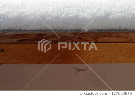 Fluffy snow lies on the wooden windowsill. Fluffy snow lies on the wooden windowsill. 127633670