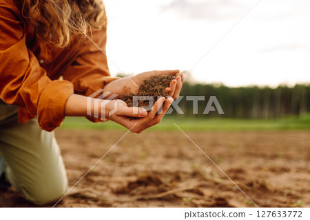 Farmer's woman's hands touch the soil in the field. Concept of gardening, agriculture. 127633772