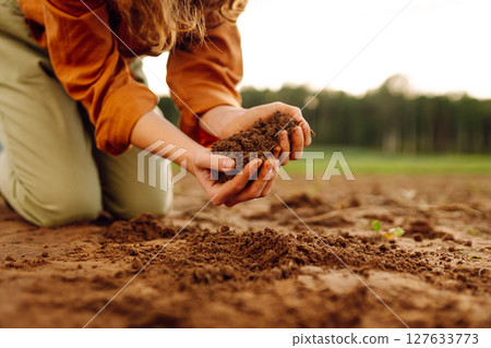 Farmer's woman's hands touch the soil in the field. Concept of gardening, agriculture. 127633773