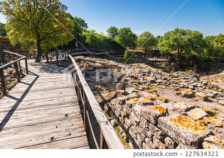 Ancient stone ruins and wooden walkway in Troy archaeological site Turkey 127634321