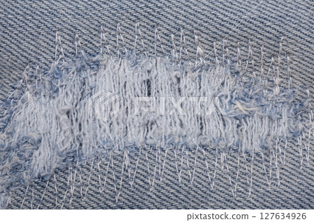 Closeup detail of torn on blue jeans. Denim jeans texture. Closeup detail of torn on blue jeans. Denim jeans texture. 127634926