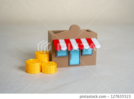 A store and a stack of money coins. Commercial real estate. Start your own business. 127635523