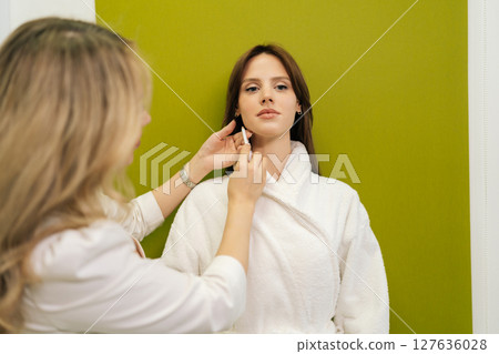 Professional beautician marking client facial contours with white pencil, preparing permanent makeup procedure in clinic of aesthetic medicine. Concept of rejuvenating skin, preventing aging. Professional beautician marking client facial contours with white pencil, preparing permanent makeup procedure in clinic of aesthetic medicine. Concept of rejuvenating skin, preventing aging. 127636028