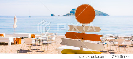 Banner wooden beach signpost with arrows on seaside promenade. Summer vacation, coastal leisure, and travel direction concept. Banner wooden beach signpost with arrows on seaside promenade. Summer vacation, coastal leisure, and travel direction concept. 127636584