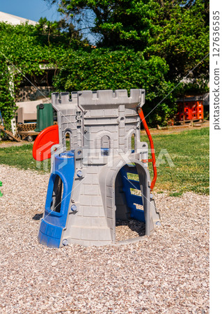 Colorful plastic playground with castle structure on gravel. Outdoor recreation, children's fun zone, and imaginative play environment concept. 127636585